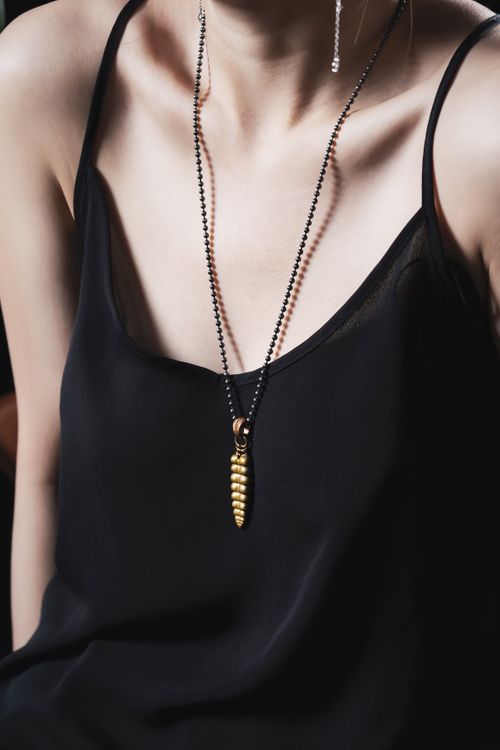 Free Close-up of a woman in a black dress wearing a trendy necklace with a golden pendant. Stock Photo