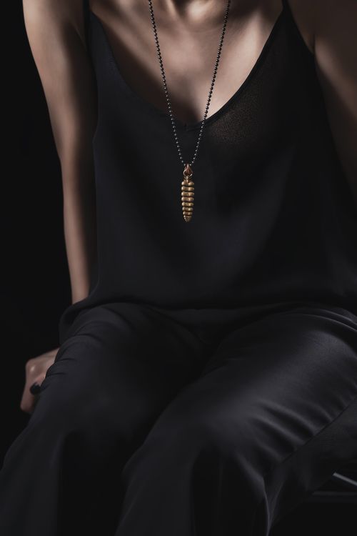 Free Fashion portrait of a woman in black clothes with a striking gold pendant necklace. Stock Photo