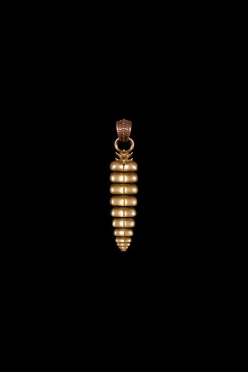 Free Gold pendant resembling a dragon tail on a black background, symbolizing elegance and craftsmanship. Stock Photo