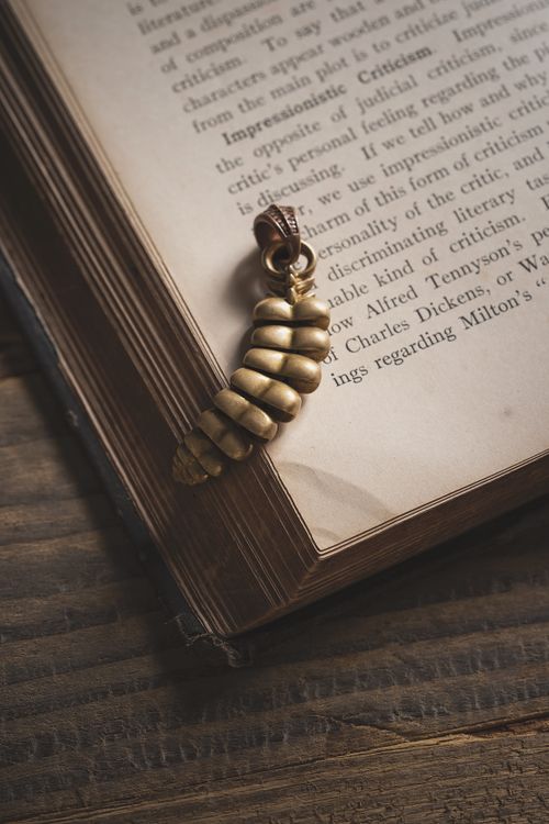 Free Close-up of an antique book with a golden jewelry bookmark resting on wooden surface. Stock Photo