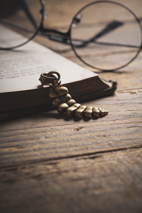 Free Artistic composition of a vintage book, eyeglasses, and golden jewelry on a wooden surface, evoking a sense of nostalgia. Stock Photo
