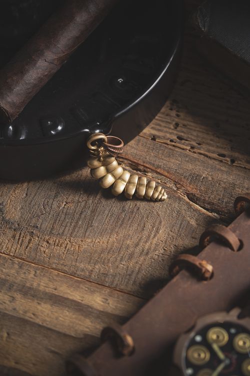 Free Detailed view of a handmade golden coil pendant with rustic accessories on a wooden surface. Stock Photo