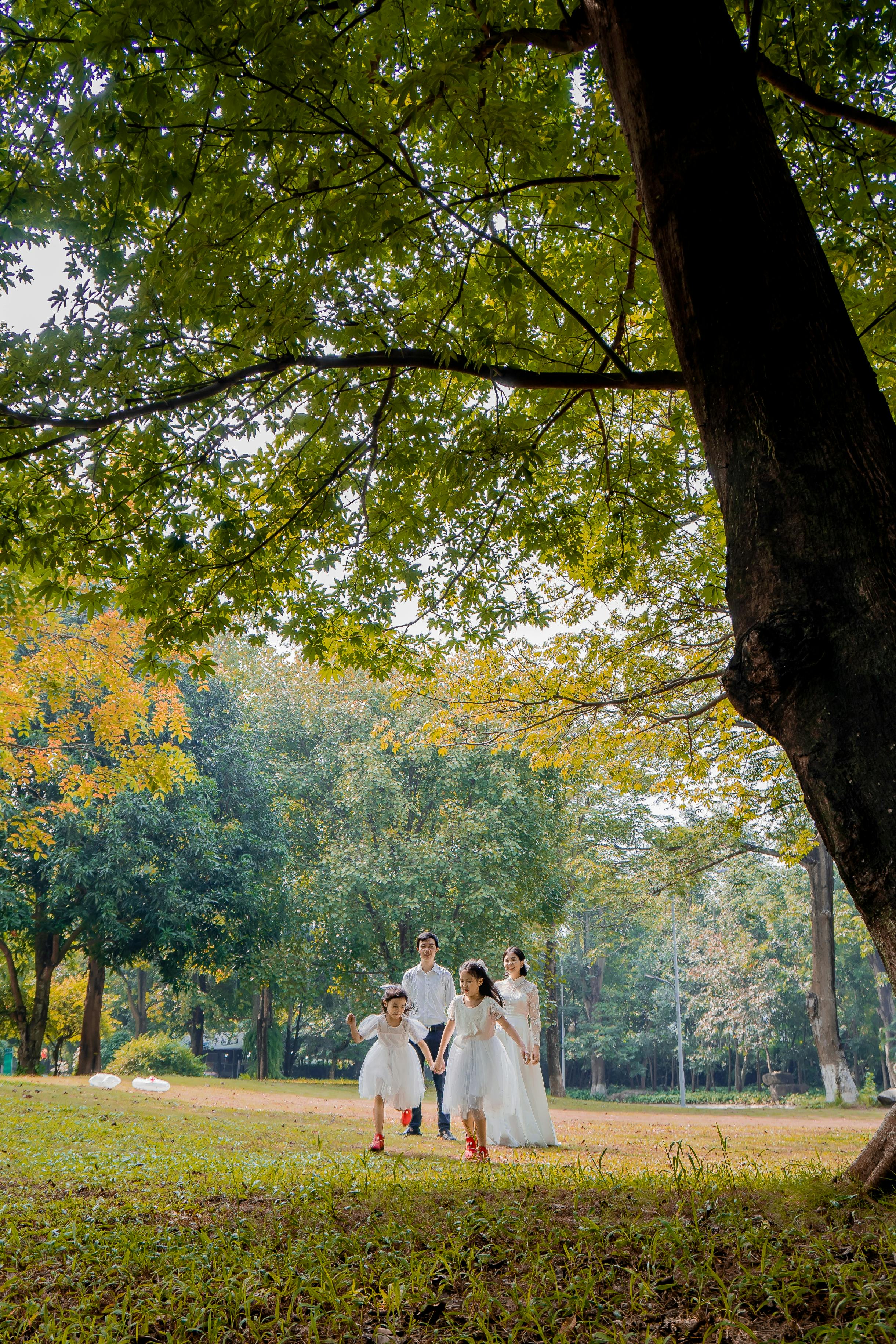 Family enjoying a walk in a vibrant green park, dressed in white for a special occasion.