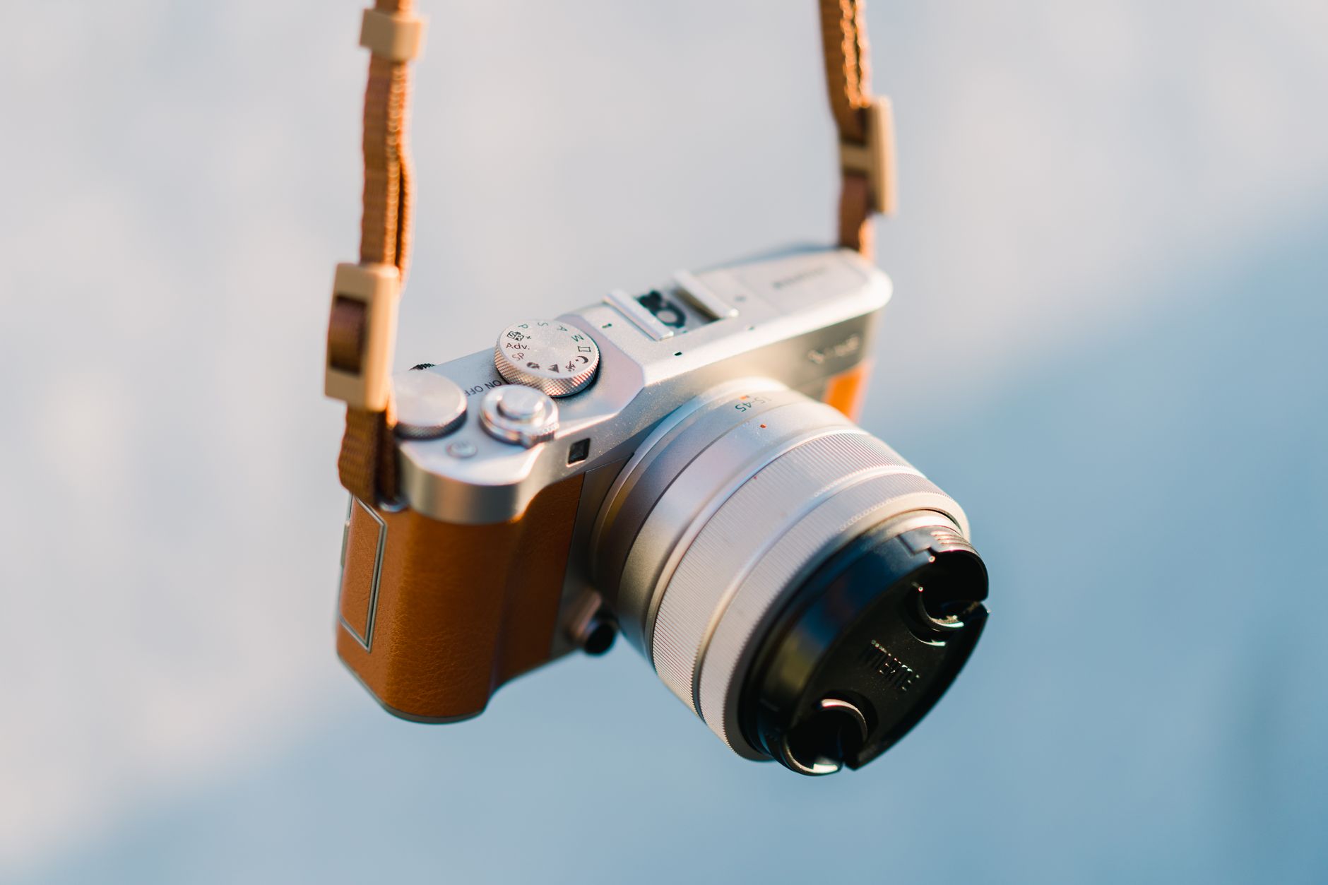 Close-up of a vintage-style camera hanging with a leather strap.