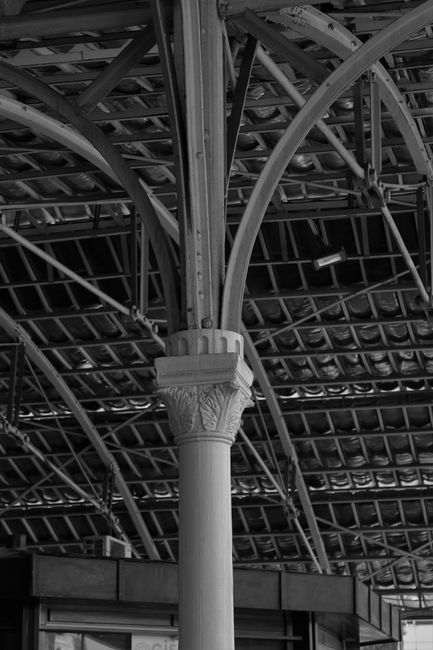 Black and white shot of a vintage ironwork structure with intricate columns and beams.