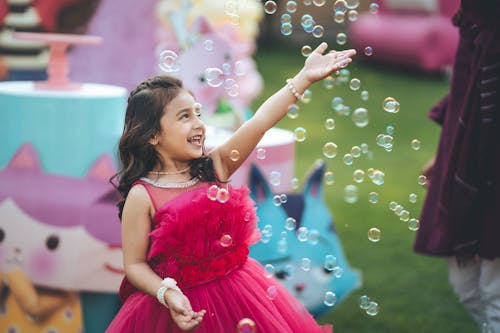 Bubbles over Smiling Girl in Pink Dress