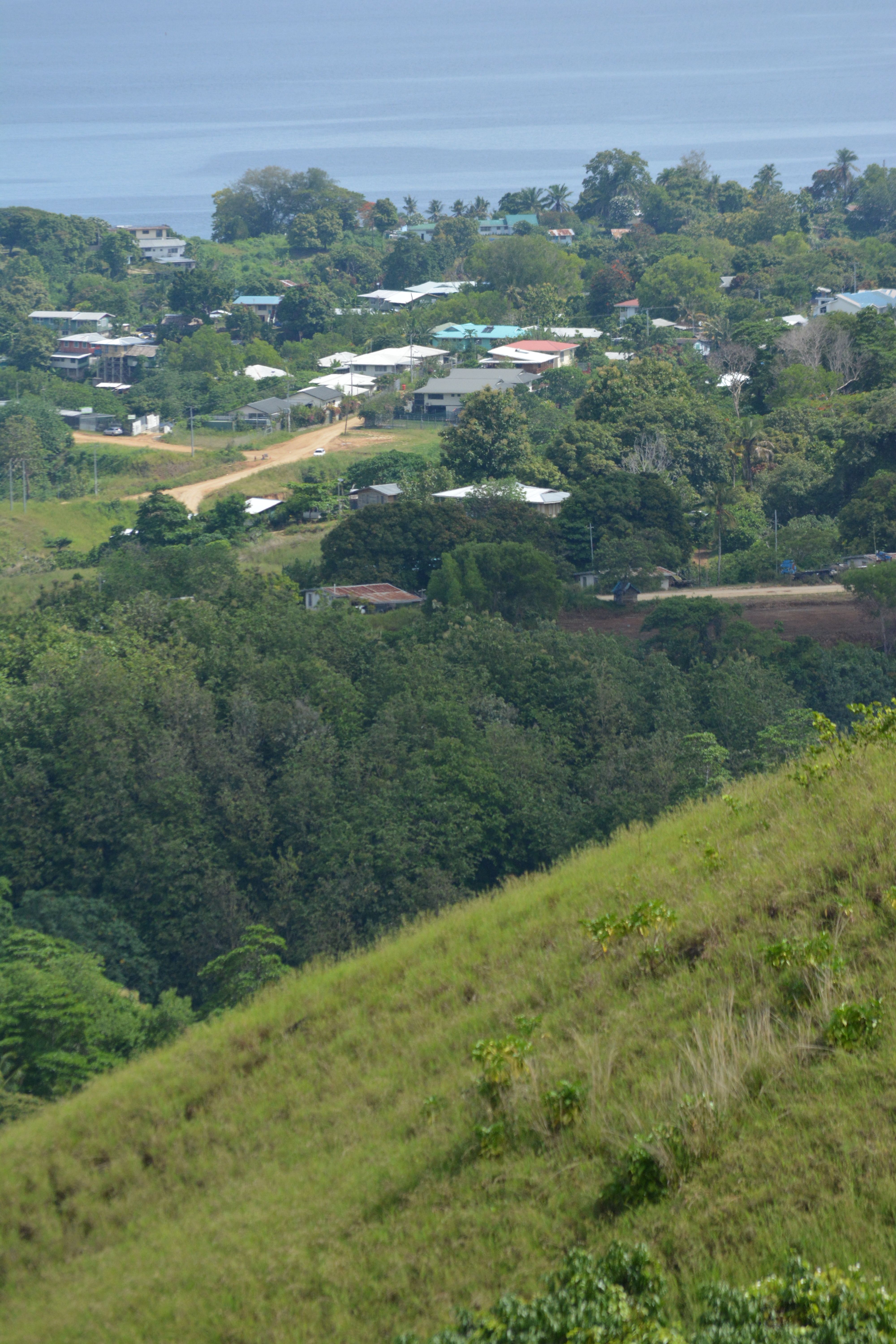 A picturesque village surrounded by lush greenery and hills under a clear sky.