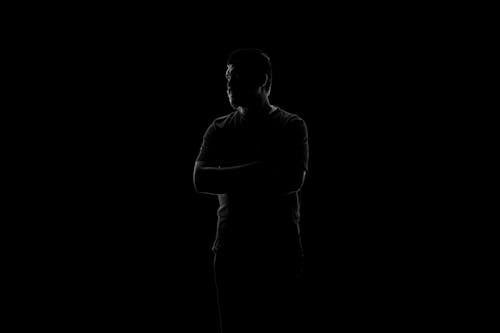 Man Standing with Arms Crossed in Darkness