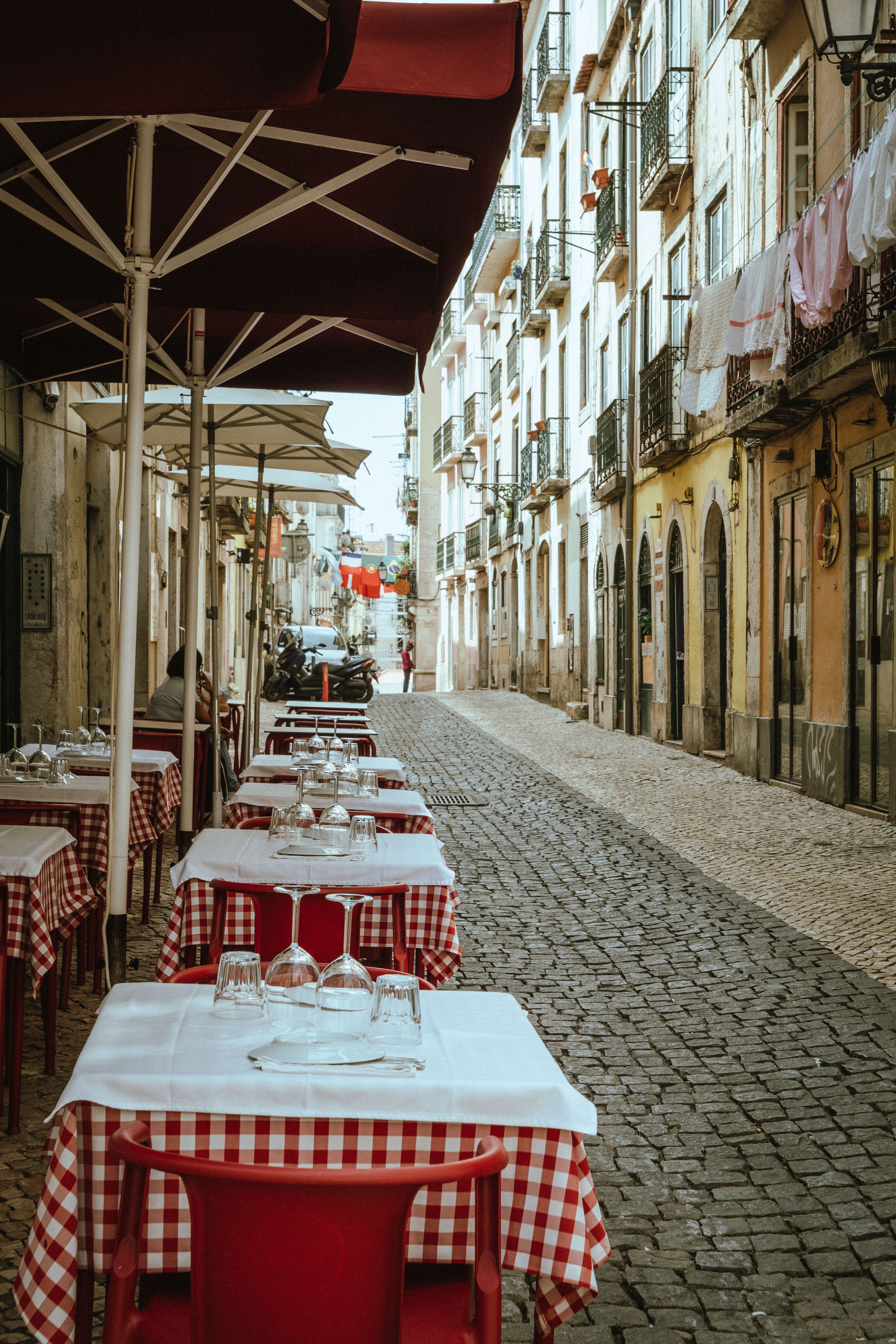 A picturesque cobblestone street in Lisbon with outdoor café tables on a spring day.