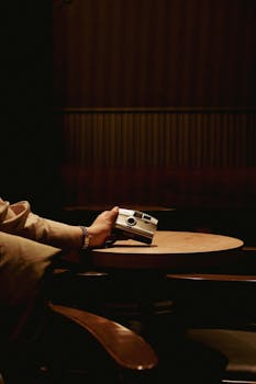 A dimly lit scene featuring a hand holding a vintage camera, evoking nostalgia.