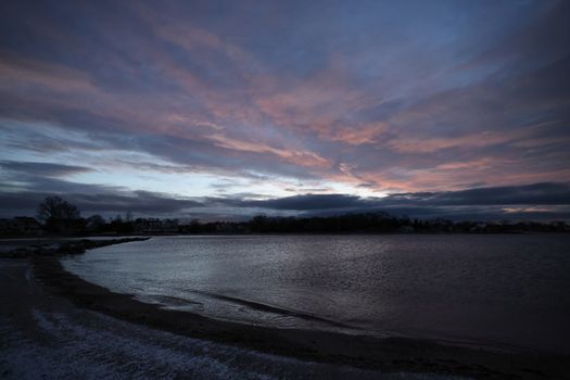 Dramatic evening sky over a tranquil coastal landscape with gentle waves.