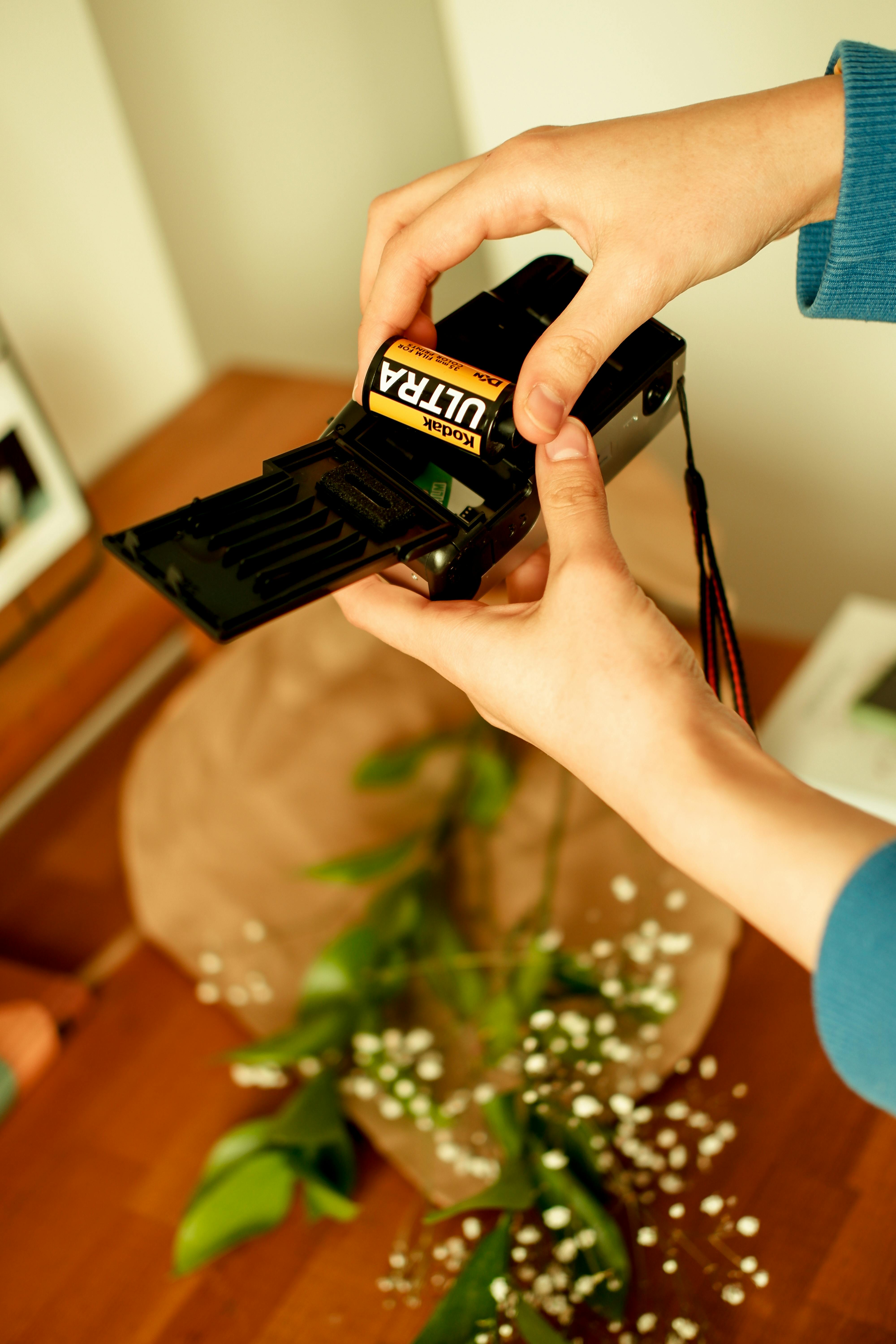 Close-up view of hands loading film into a vintage camera, showcasing analog photography