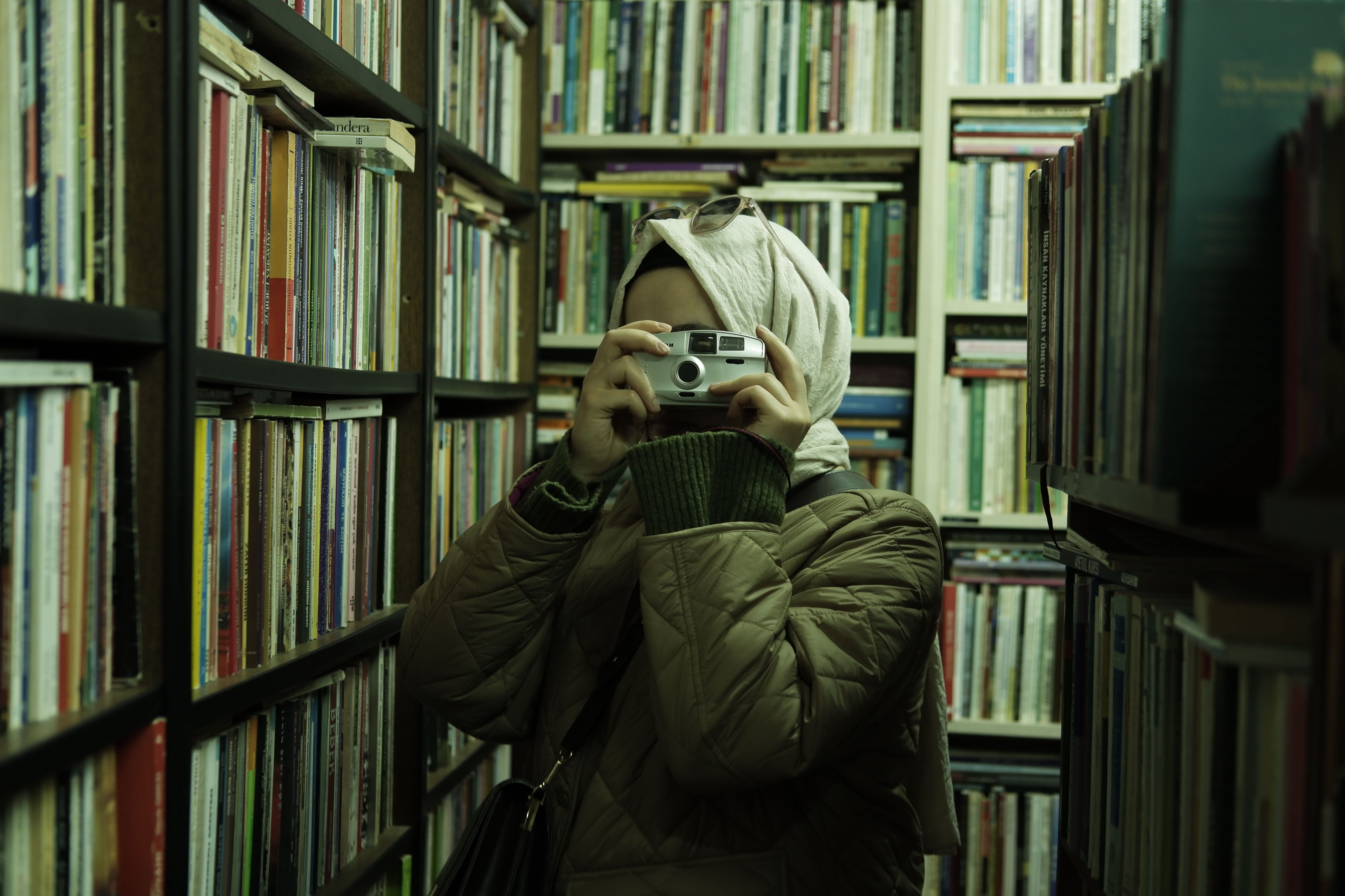 Woman Holding a Camera in a Library · Free Stock Photo