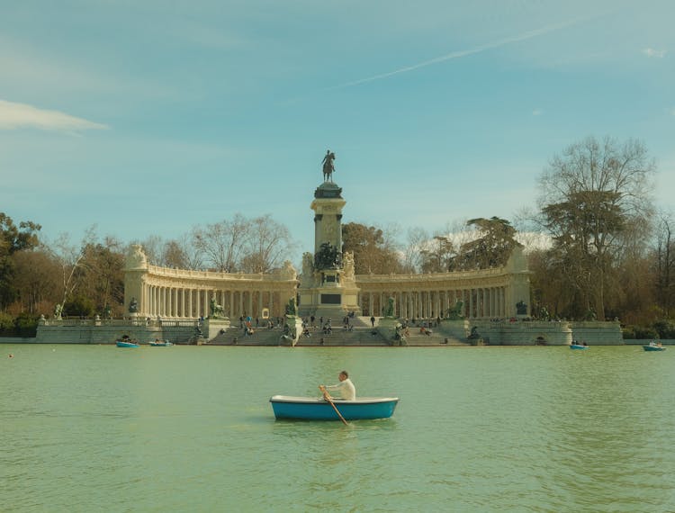 Man Rowing Boat Under Monument To Alfonso XII In Madrid, Spain