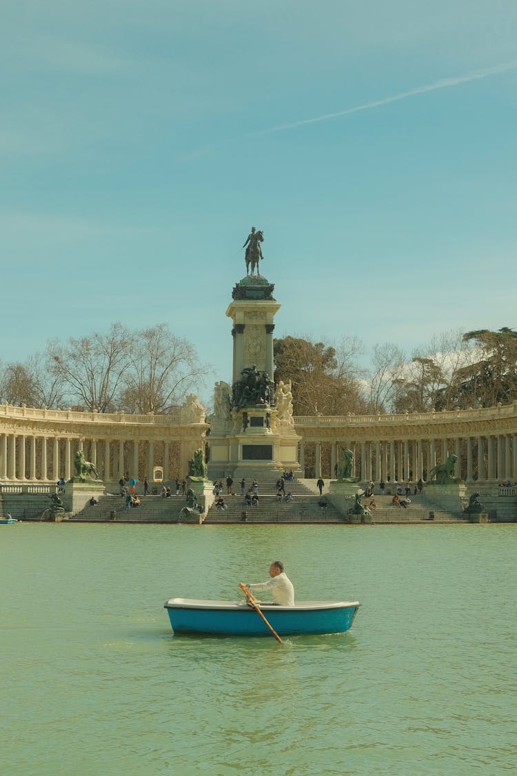 Man Rowing Across Great Pond Of El Retiro In Madrid, Spain