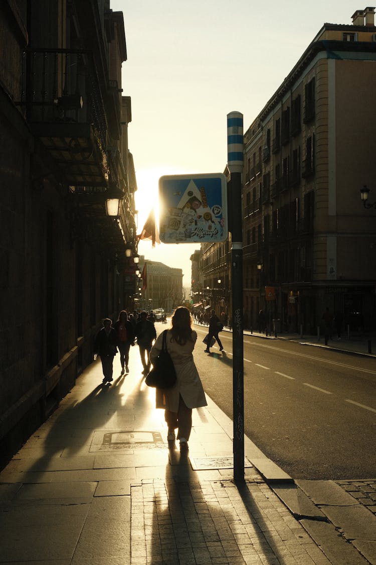 Silhouettes Of People Walking Down Street At Sunset