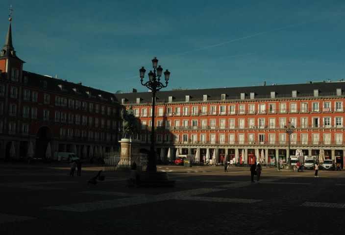 Sunlit view of historic Plaza Mayor in Madrid, showcasing architecture and daily life.