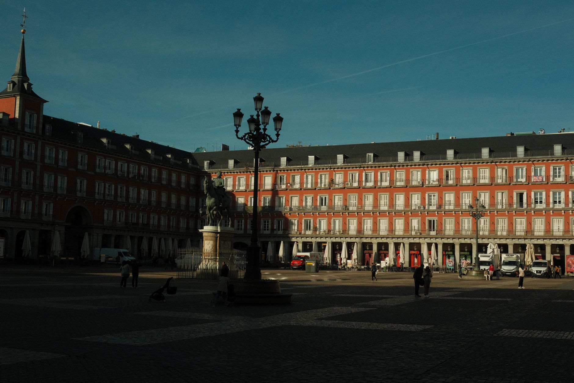 Sunlit view of historic Plaza Mayor in Madrid, showcasing architecture and daily life.