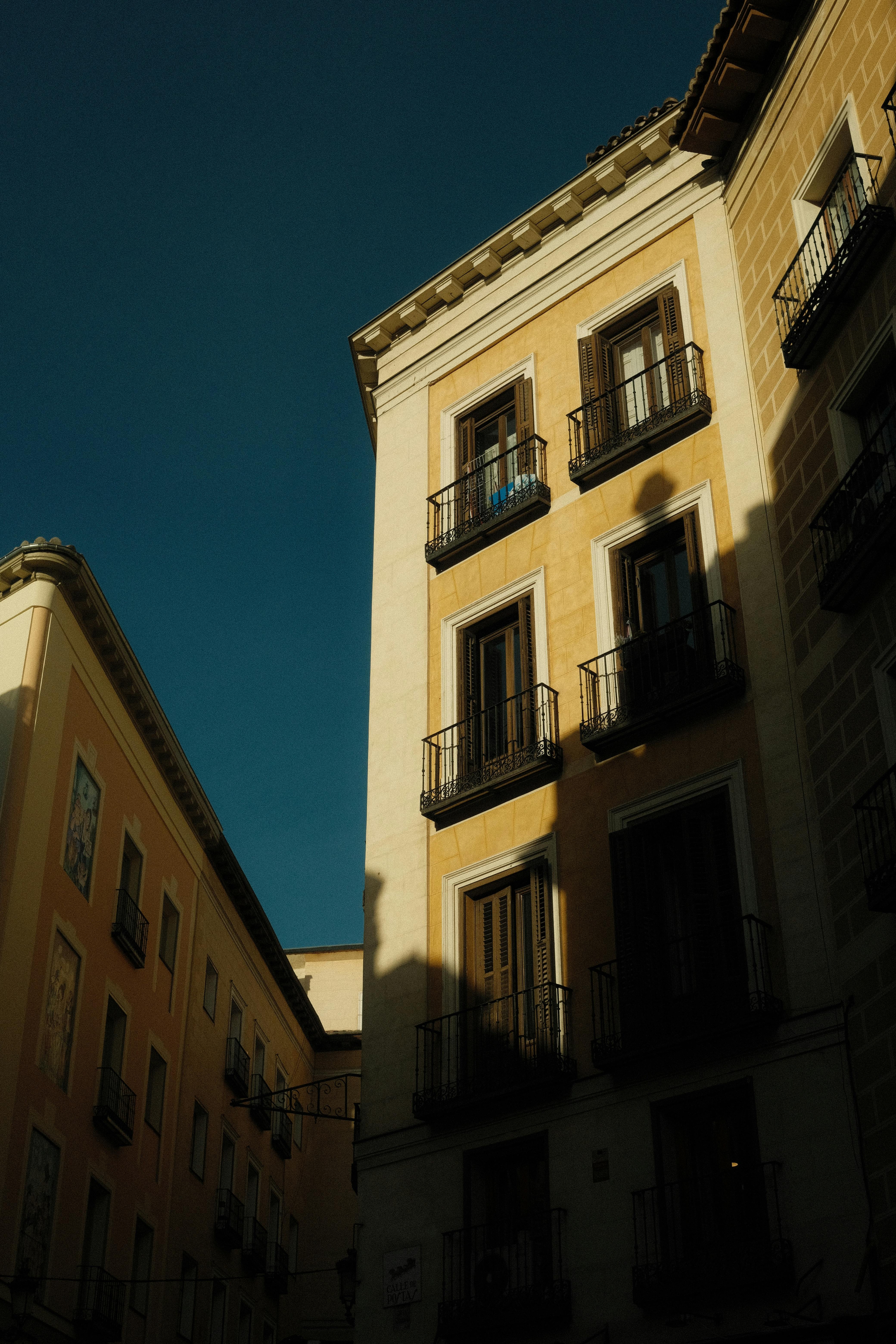 Vertical shot of sunlit European buildings with dramatic shadows and a clear sky.