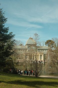 View of Palacio de Cristal in Madrid with people gathered in the park on a sunny day.
