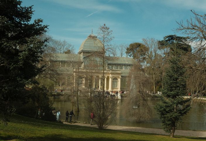 A picturesque view of the Crystal Palace surrounded by trees in a Madrid park.