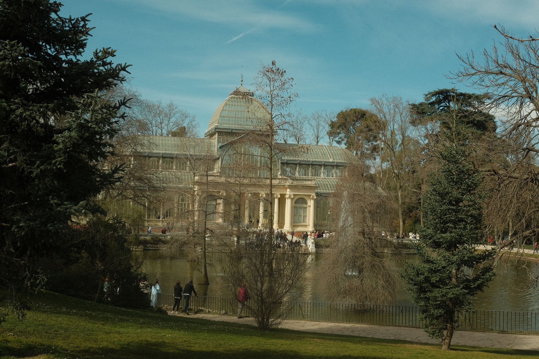 A picturesque view of the Crystal Palace surrounded by trees in a Madrid park.