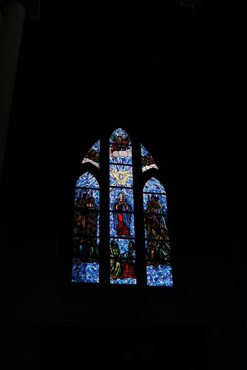 Free A stunning stained glass window depicting religious scenes in a dark church interior. Stock Photo