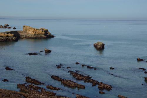 Free Peaceful coastal scene with rocks and clear sea under a calm blue sky, ideal for serene settings. Stock Photo