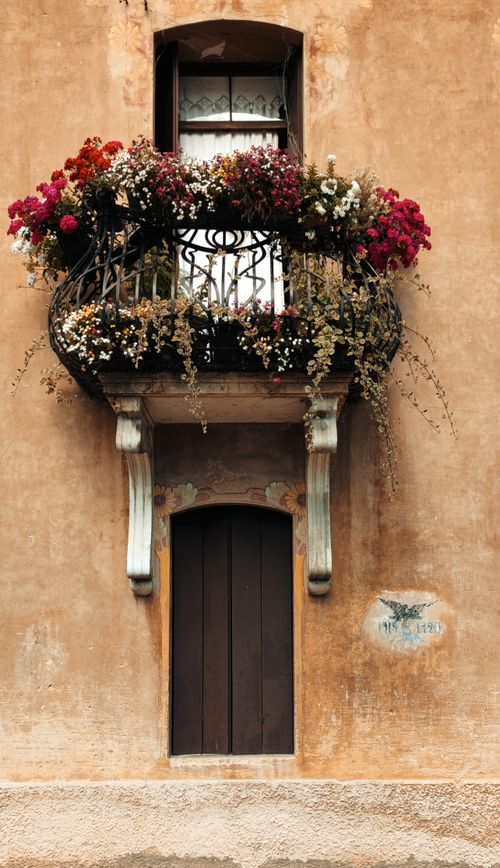 Free Rustic balcony with vibrant flowers in Cison di Valmarino, Italy. Perfect for travel and architecture enthusiasts. Stock Photo