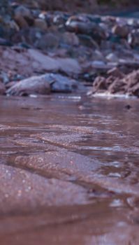 Tranquil scene of a riverbank with gentle water flow and natural rocks, perfect for nature themes.