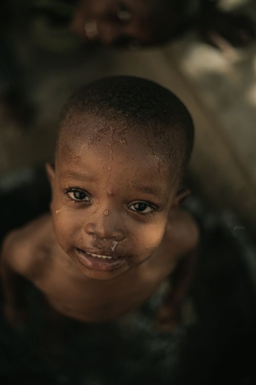 Free A young child smiles during an outdoor bath, capturing a moment of joy and innocence. Stock Photo