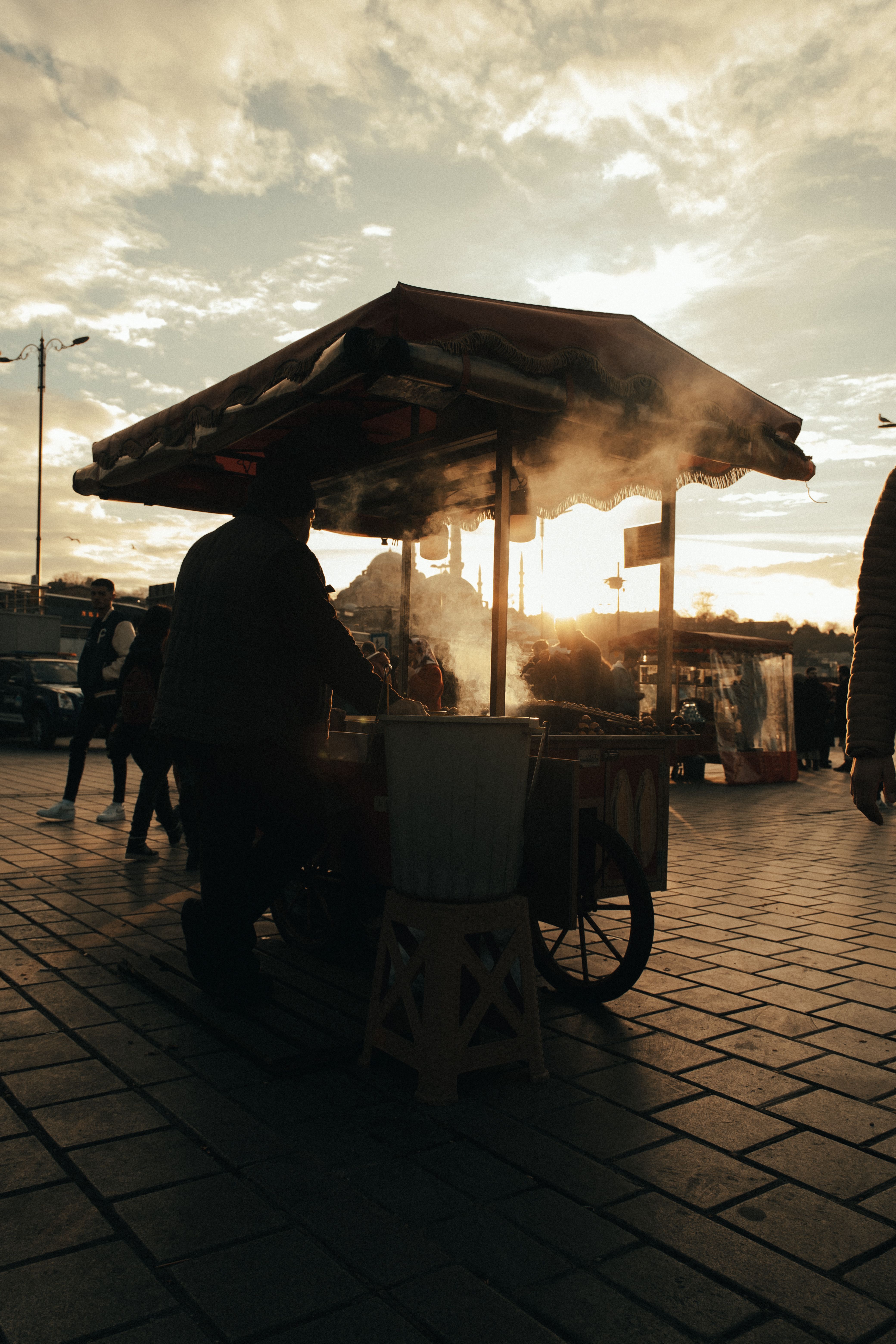 Street food vendor silhouetted against a sunset sky