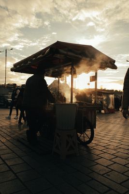 Street food vendor silhouetted against a sunset sky