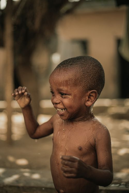 Free A young boy enjoys a playful moment with water, showcasing joy and laughter. Stock Photo
