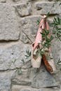 Two ballet shoes hanging from a stone wall