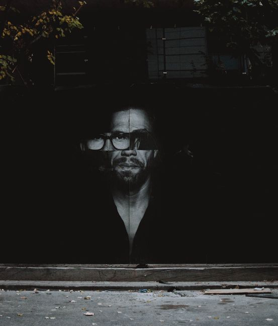 A striking mural of a man's face with glasses in urban Frankfurt.