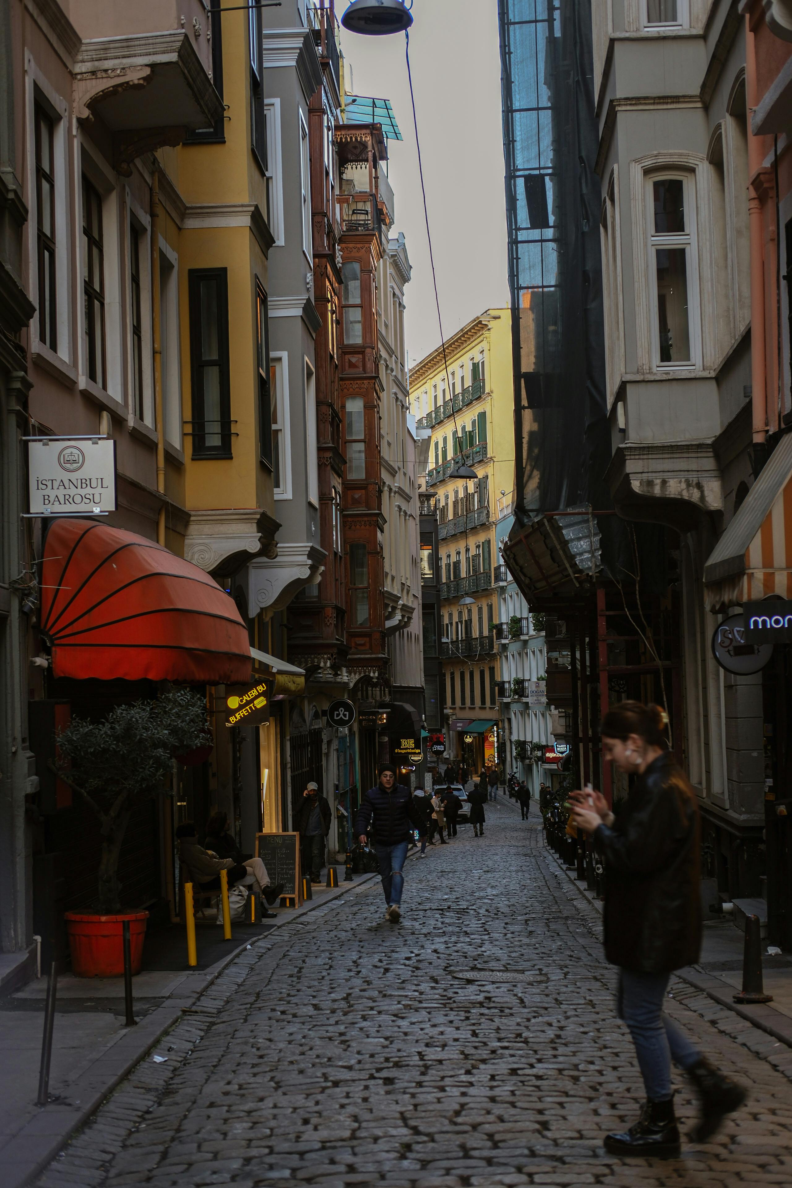 a person walking down a narrow street with a cable car