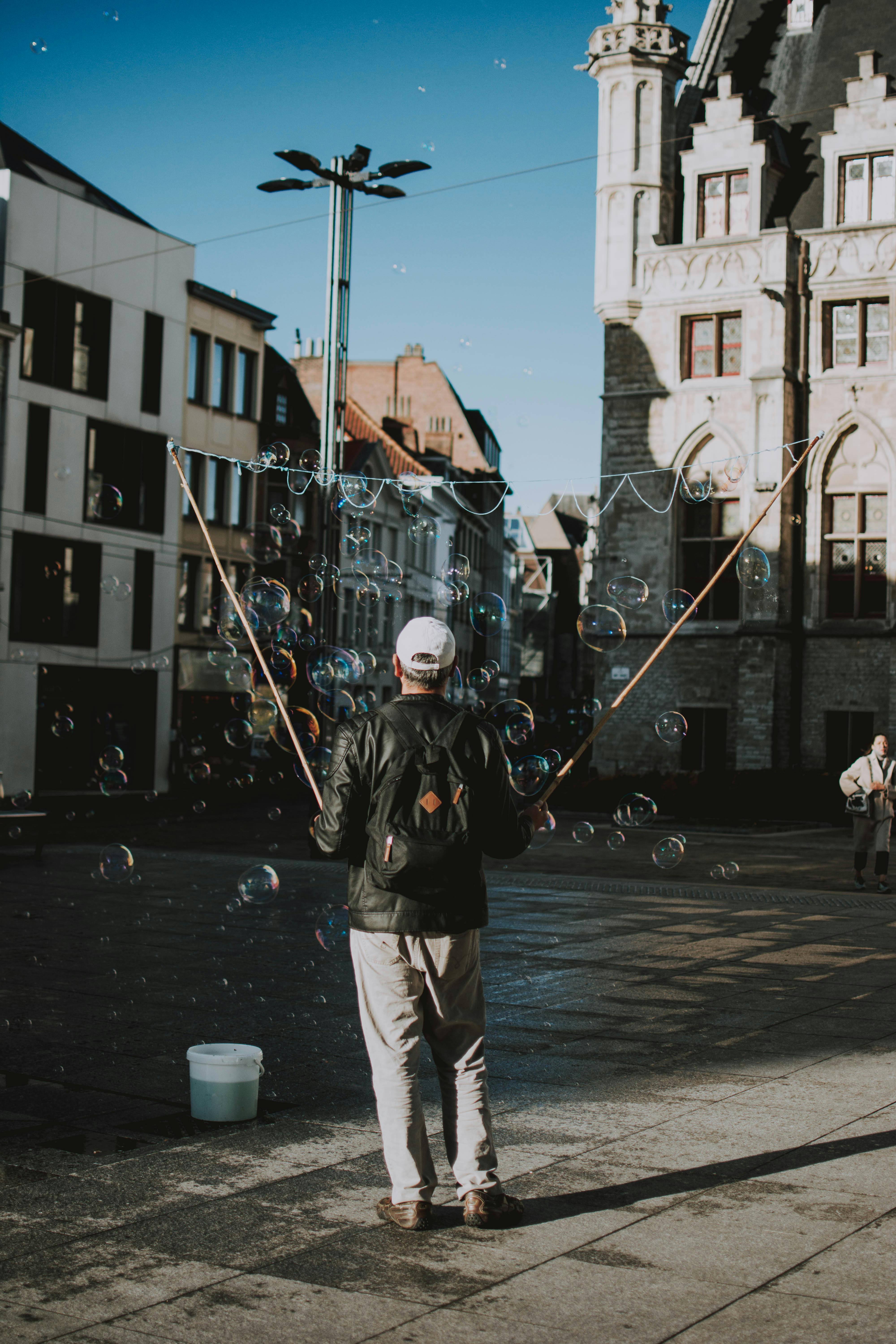 A street performer makes giant bubbles in a bustling Brussels square.
