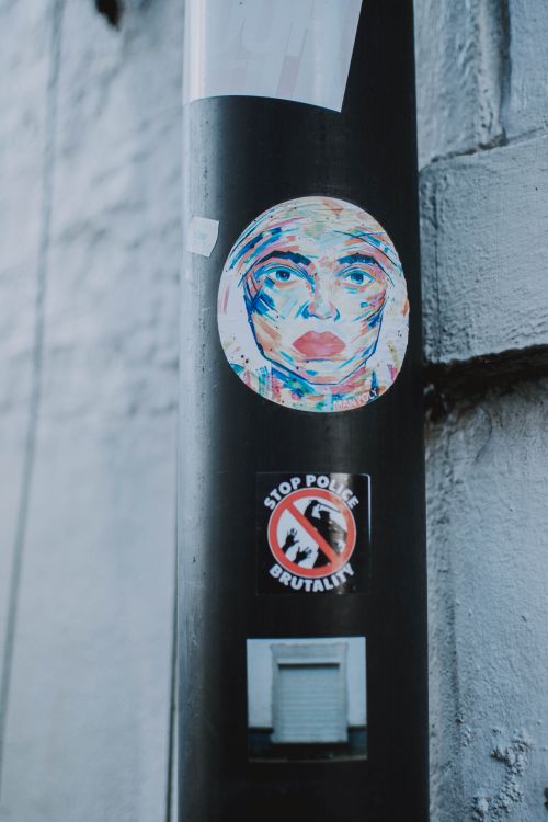 Free Street art and protest stickers on a pole in Brussels, Belgium showcasing creativity and social messages. Stock Photo