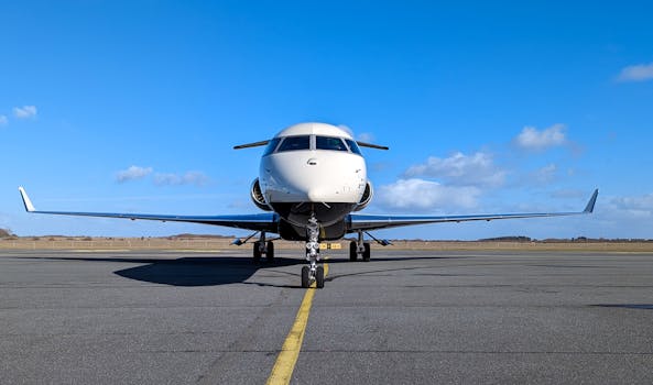 A large airplane symmetrically parked on a runway with a clear blue sky.