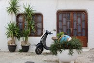 Vintage scooter and potted plants outside rustic house in Peniscola, Spain.