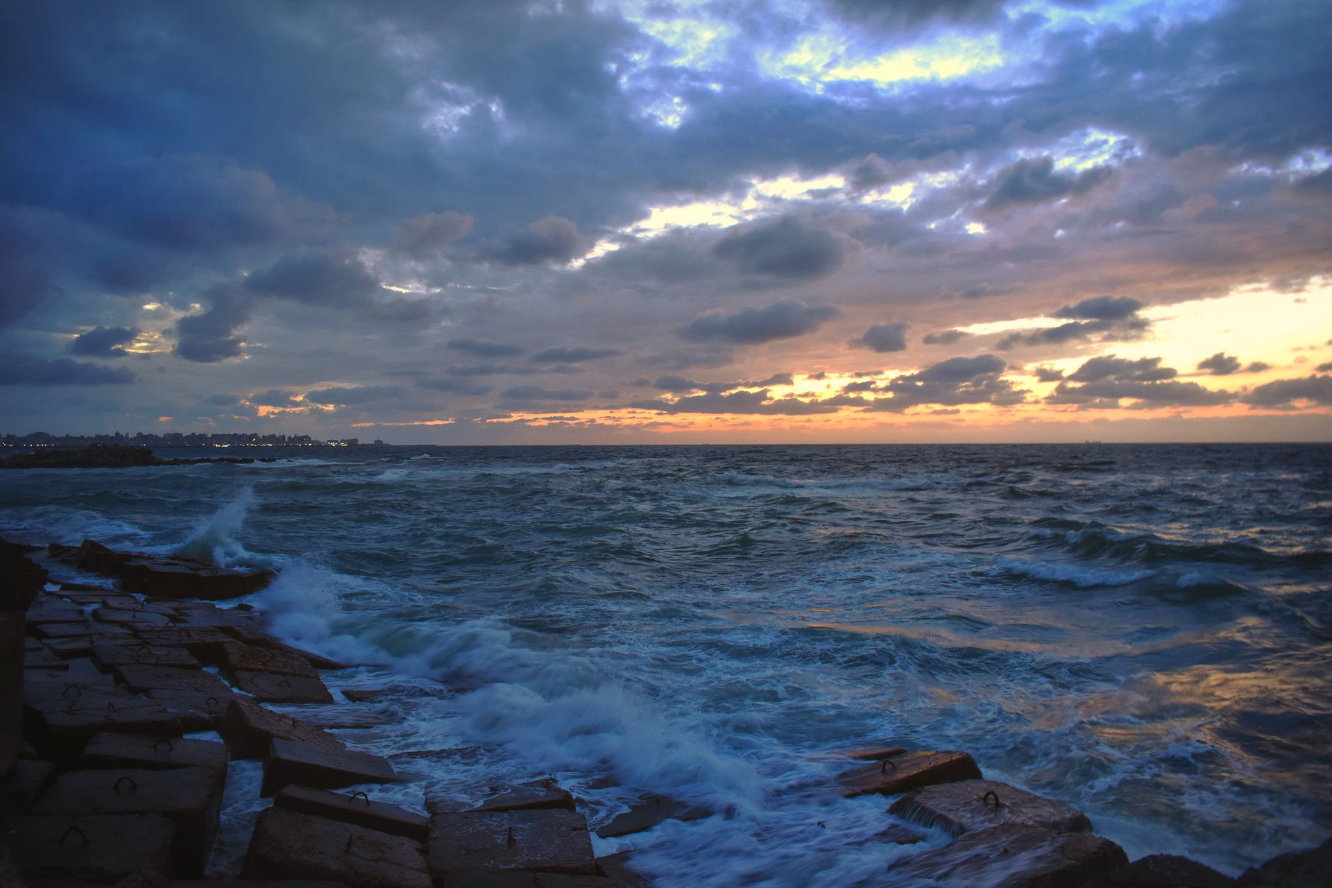Calm Mediterranean coastline at dusk with horizon clouds