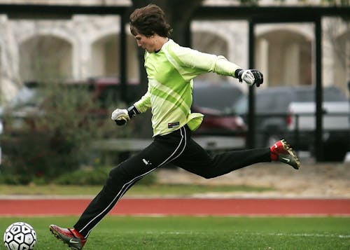 Man in Black Pants Playing Soccer during Daytime