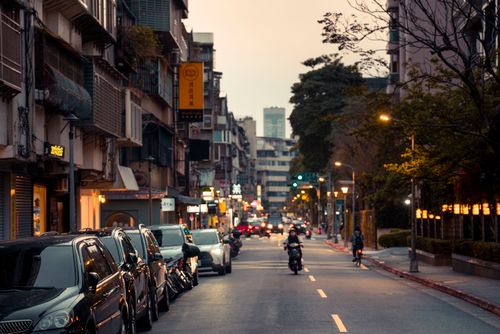 Free Capture of a bustling city street in the evening, featuring cars and motorcycles. Stock Photo