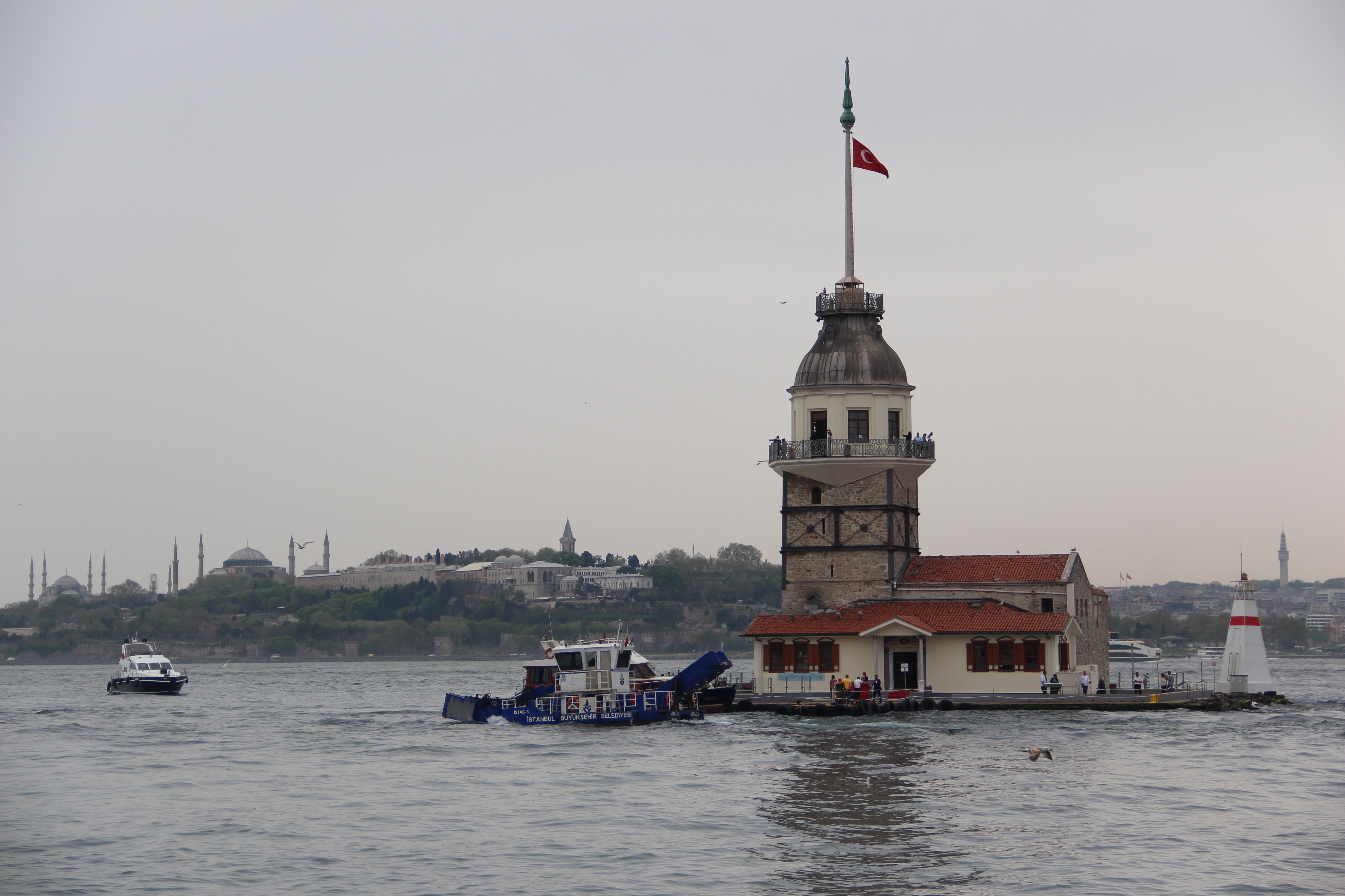Scenic view of Maiden's Tower in Istanbul on the Bosphorus Strait with boats and a cloudy sky.