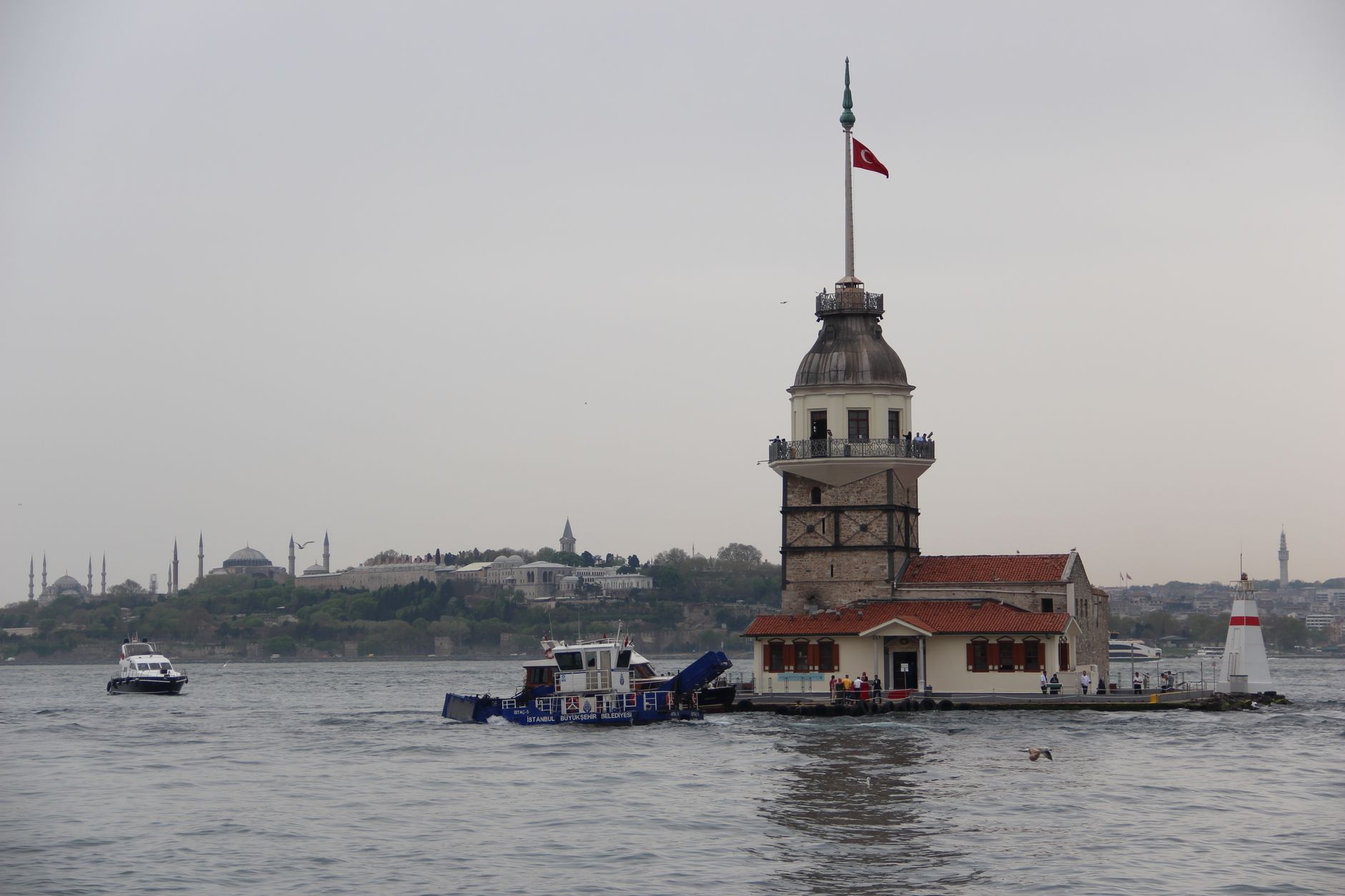 Scenic view of Maiden's Tower in Istanbul on the Bosphorus Strait with boats and a cloudy sky.