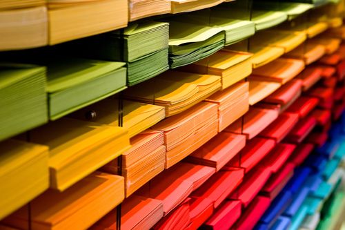 Free Vibrant multicolored paper stacks arranged on shelves in a stationery store. Stock Photo