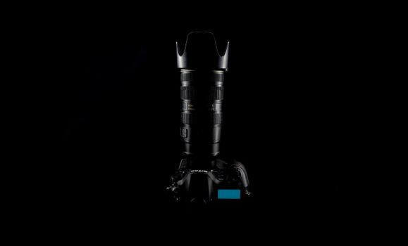 A professional DSLR camera with a telephoto lens against a dark background.