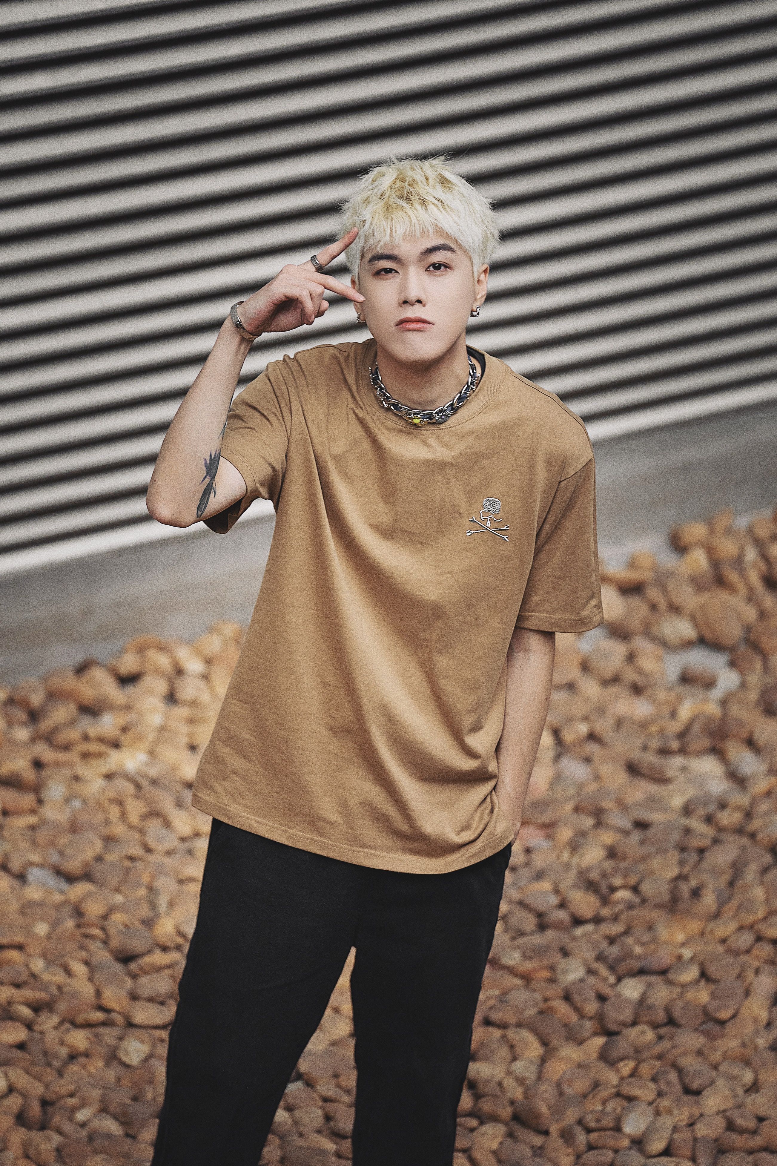 Young man with platinum hair posing outdoors in casual streetwear.