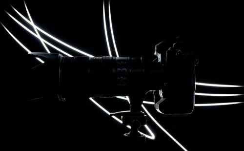 Free Artistic silhouette of a DSLR camera with striking white light trails on a dark background. Stock Photo